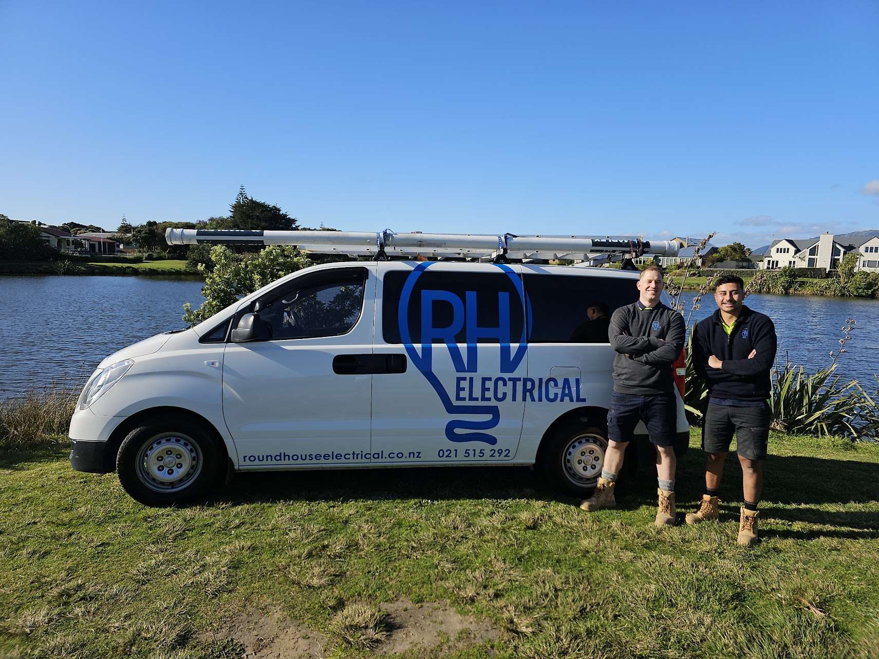 Two smiling men in front of work vehicle